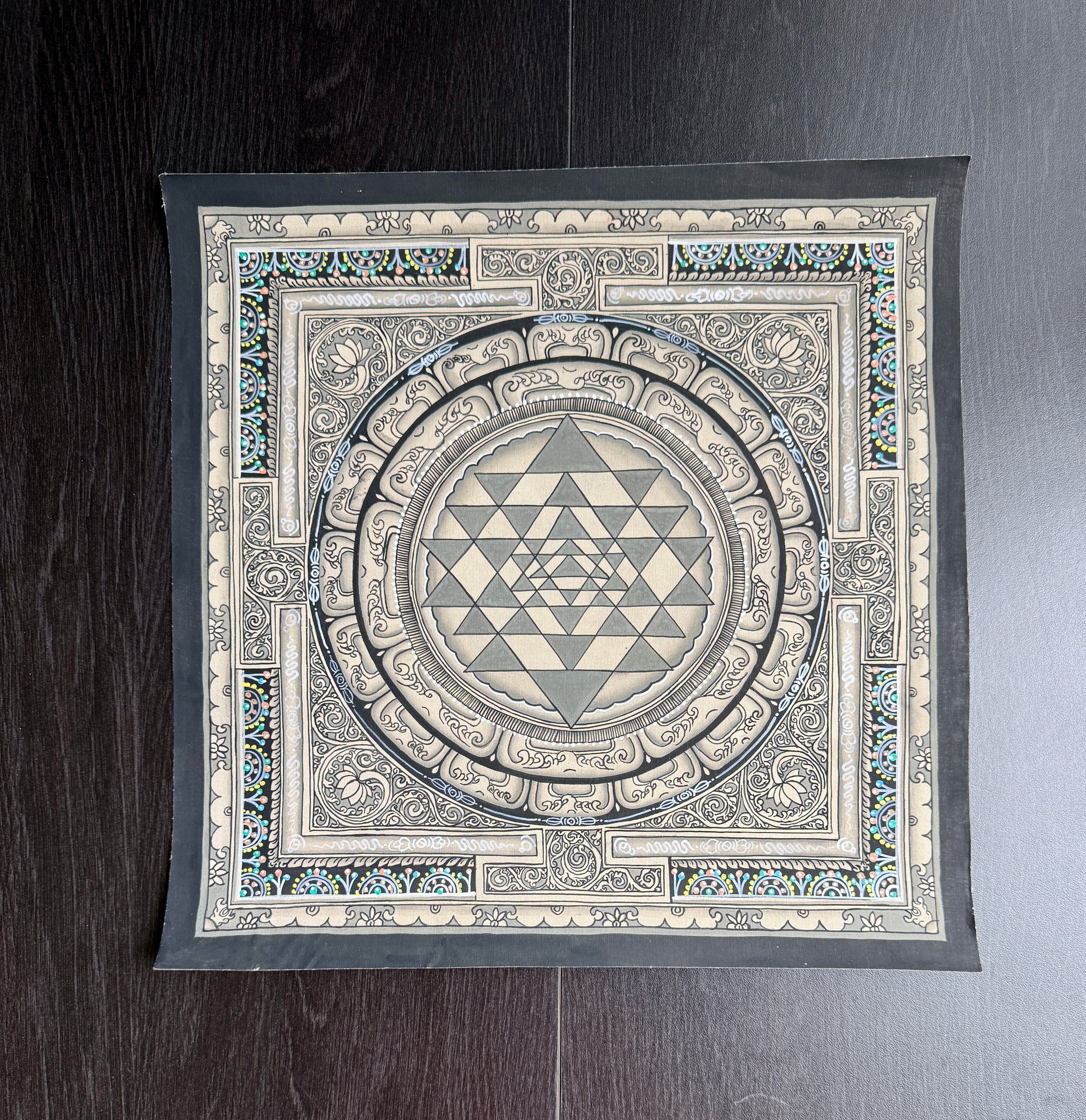 Shree yantra painting in Thangka art style with a geometric design on a wooden surface
