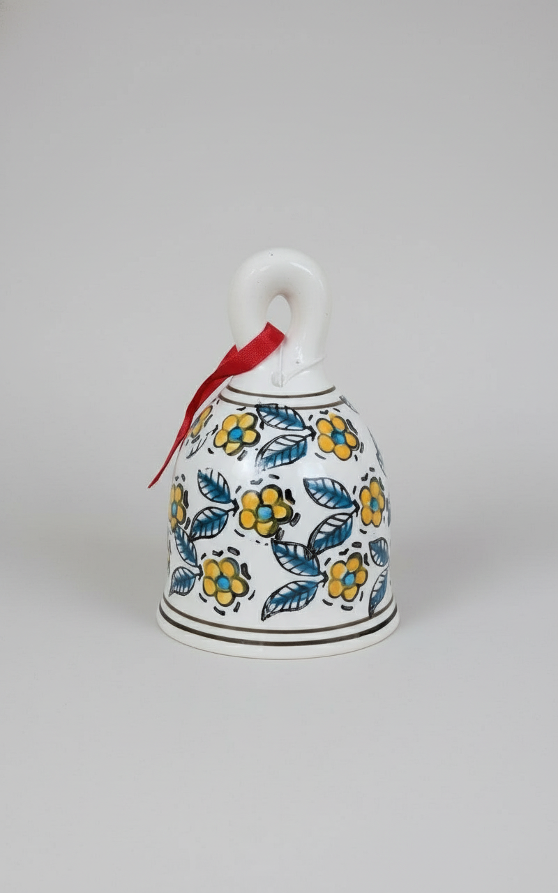 Decorative bell with floral patterns and a red ribbon on a white background