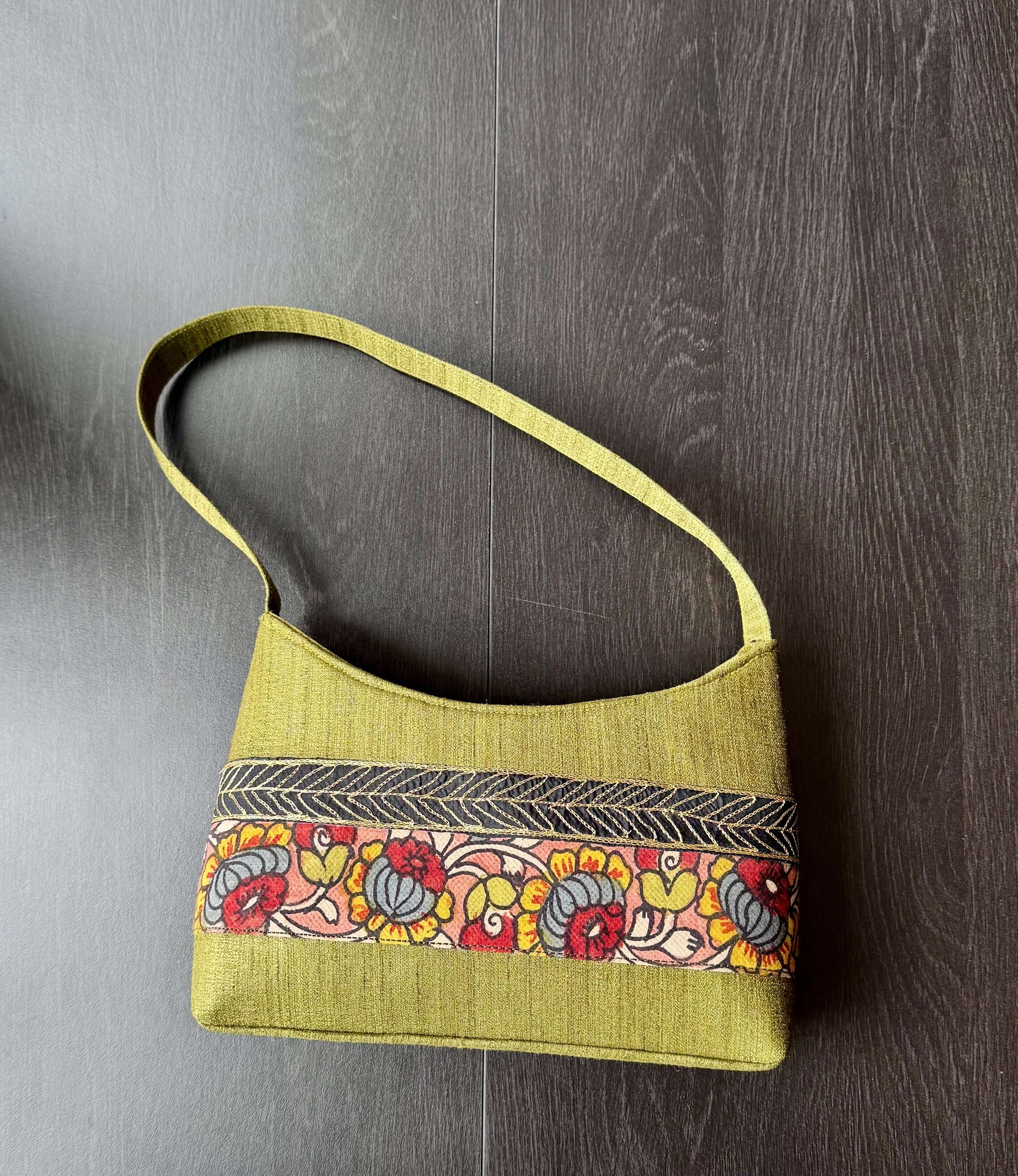 Green handbag with floral pattern on a wooden surface