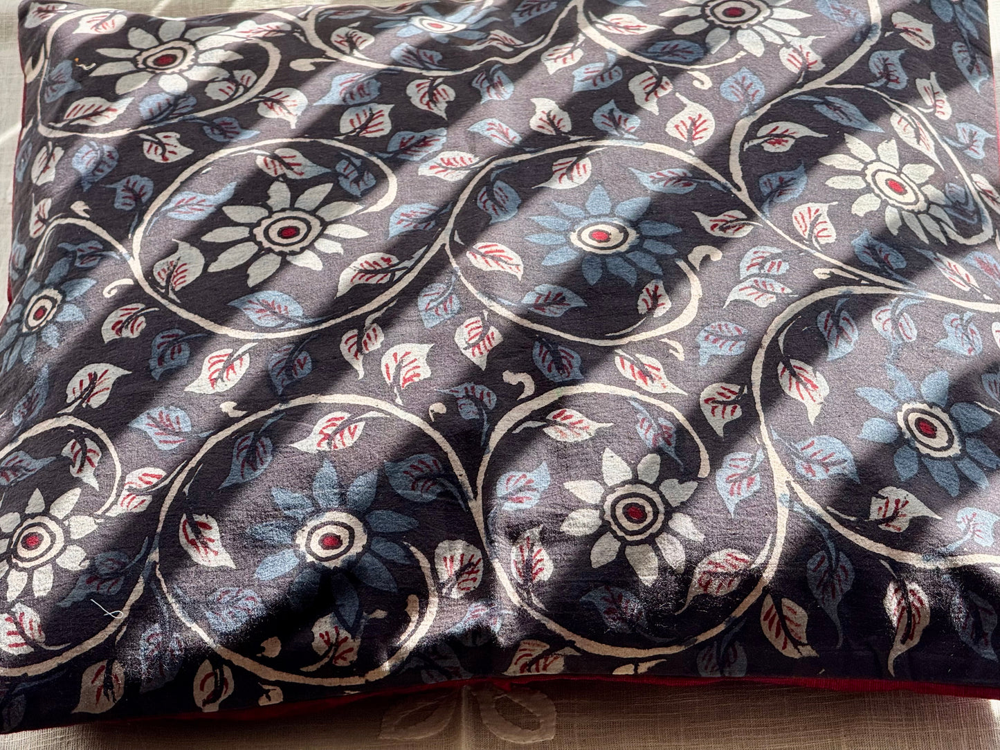 A set of artisanal Kalamkari hand-painted cushion covers with vibrant and intricate patterns laid out on a surface.