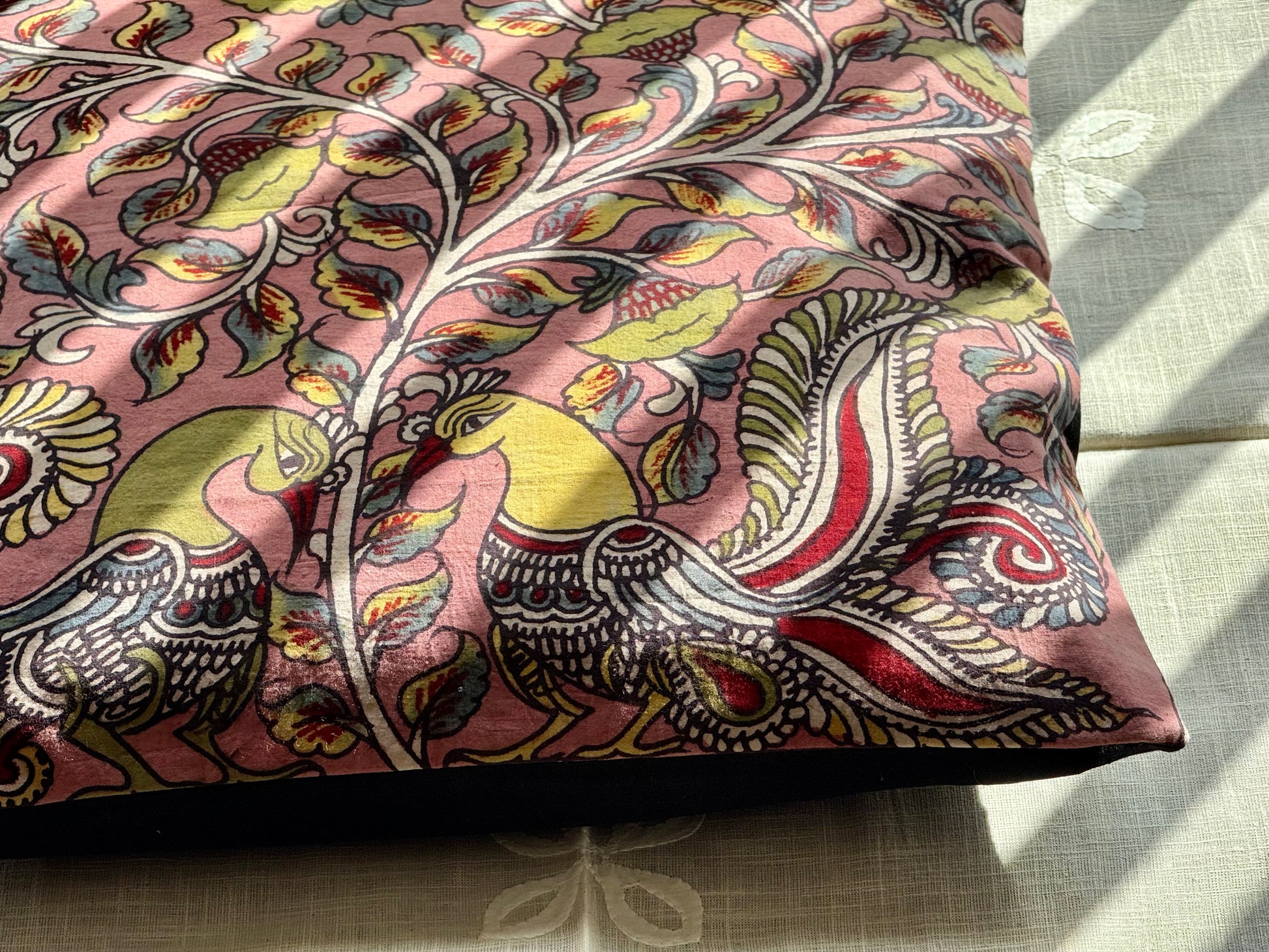 A set of artisanal Kalamkari hand-painted cushion covers with vibrant and intricate patterns laid out on a surface.