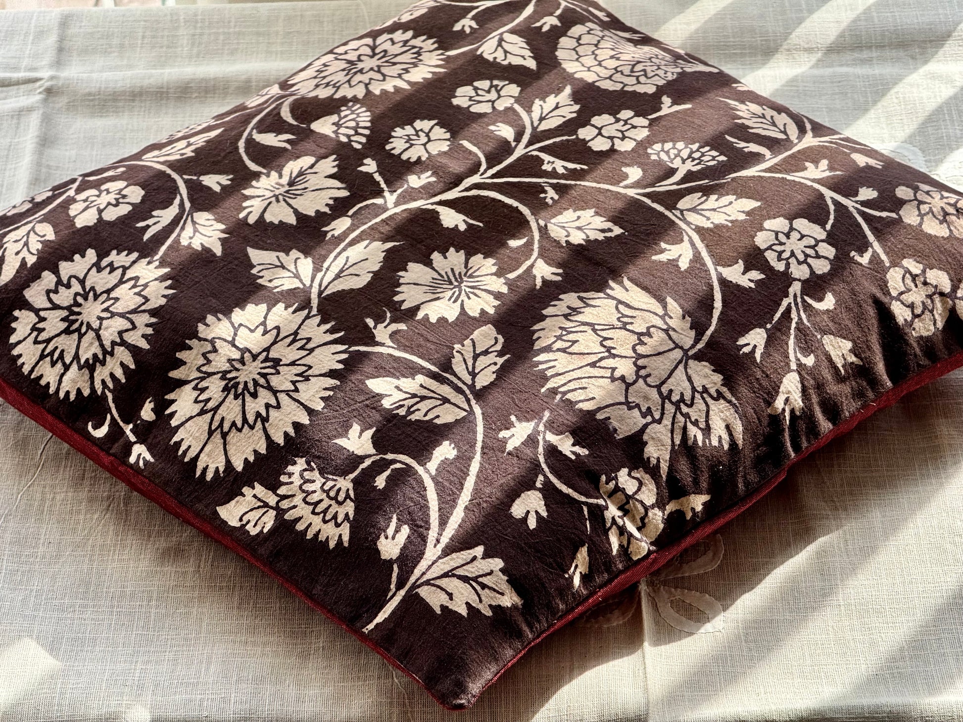 A set of artisanal Kalamkari hand-painted cushion covers with vibrant and intricate patterns laid out on a surface.