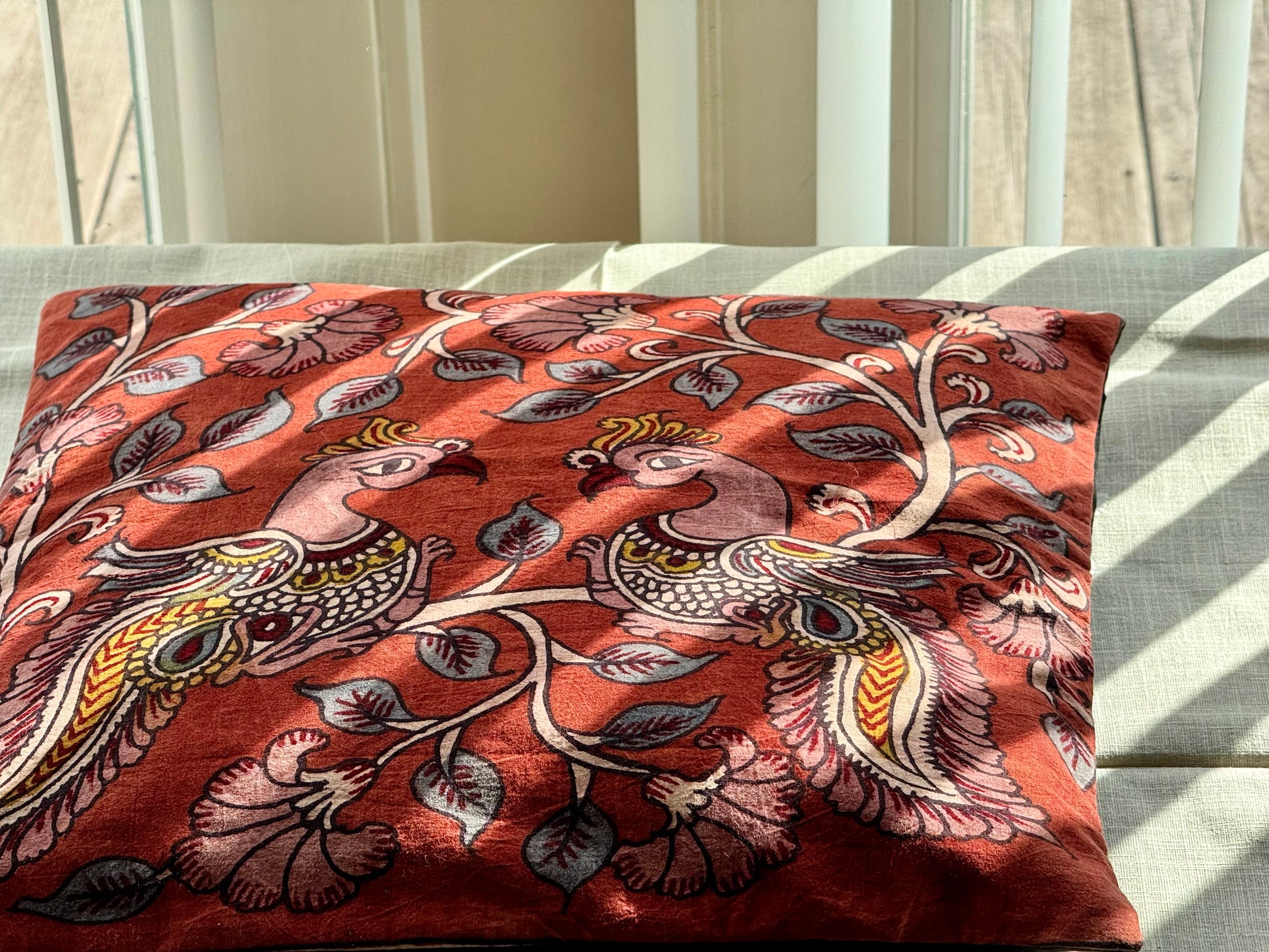 A set of artisanal Kalamkari hand-painted cushion covers with vibrant and intricate patterns laid out on a surface.