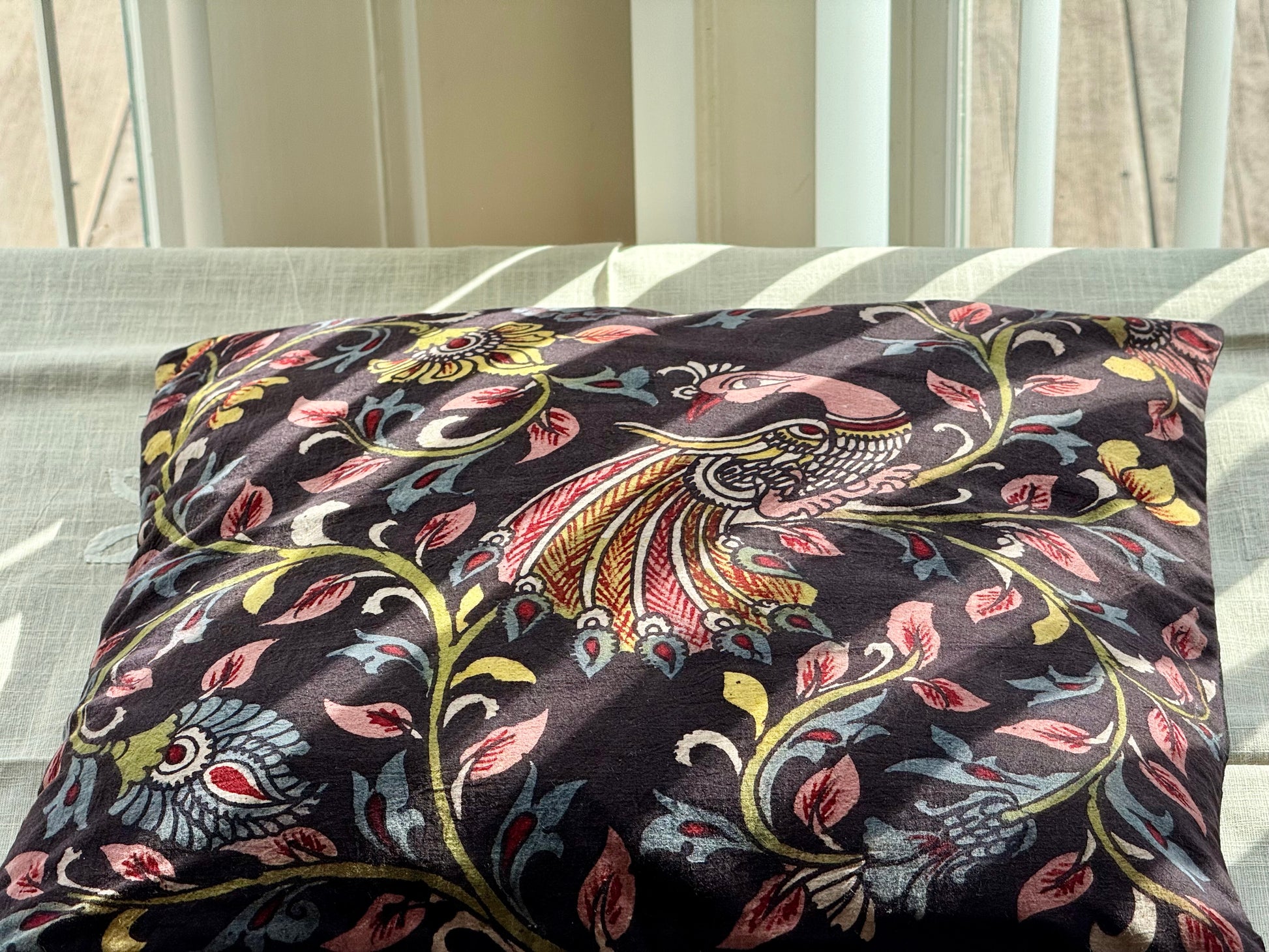 A set of artisanal Kalamkari hand-painted cushion covers with vibrant and intricate patterns laid out on a surface.