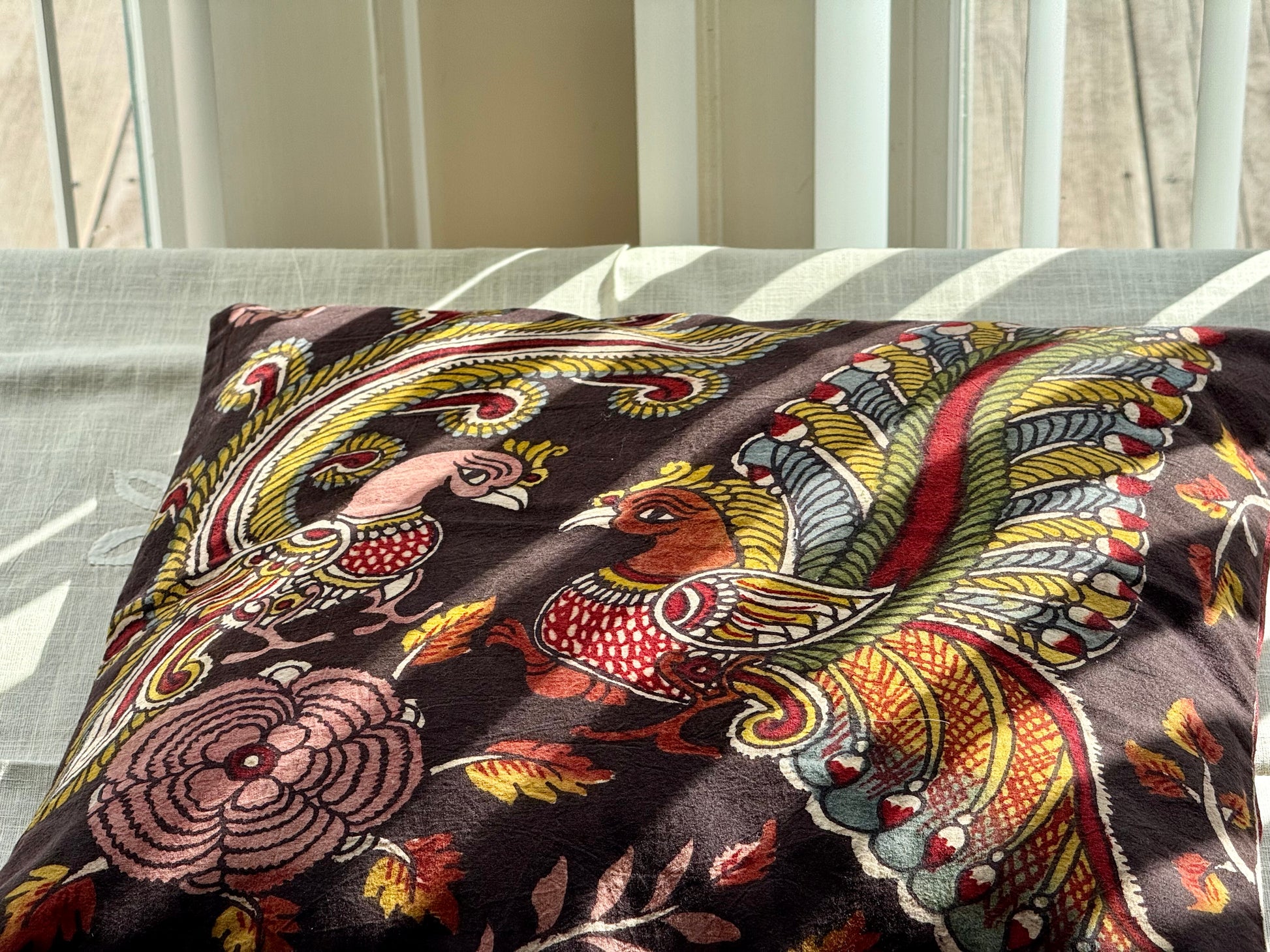 A set of artisanal Kalamkari hand-painted cushion covers with vibrant and intricate patterns laid out on a surface.