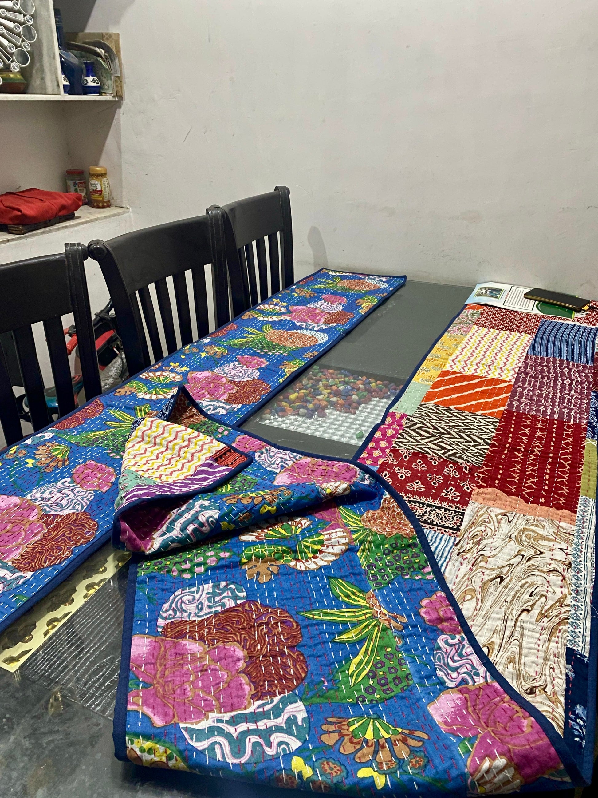 Colorful Kantha work reversible table runners with floral patterns on a table with chairs in a room.