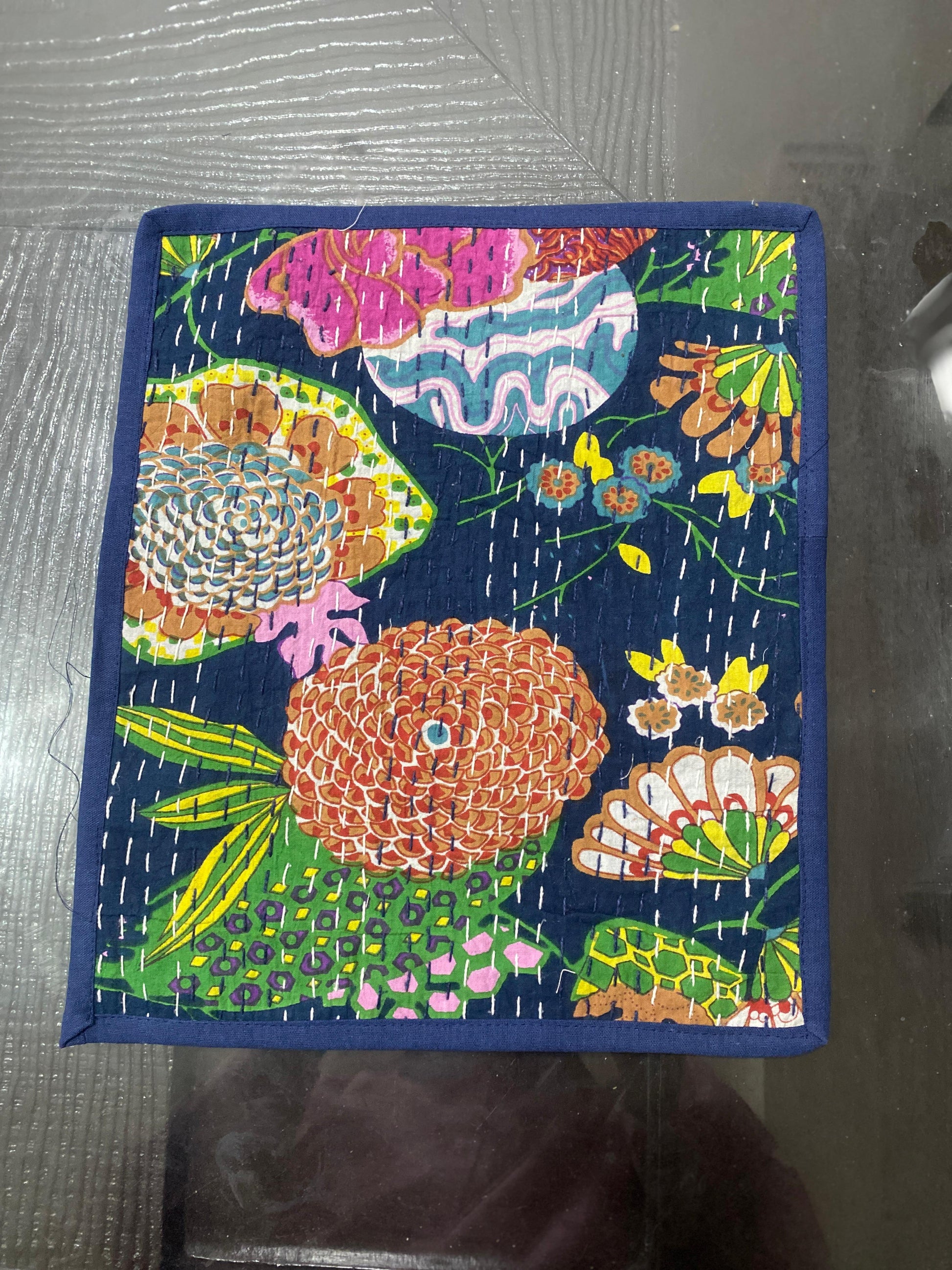 Colorful floral patterned fabric Kantha work placemat on a dark background