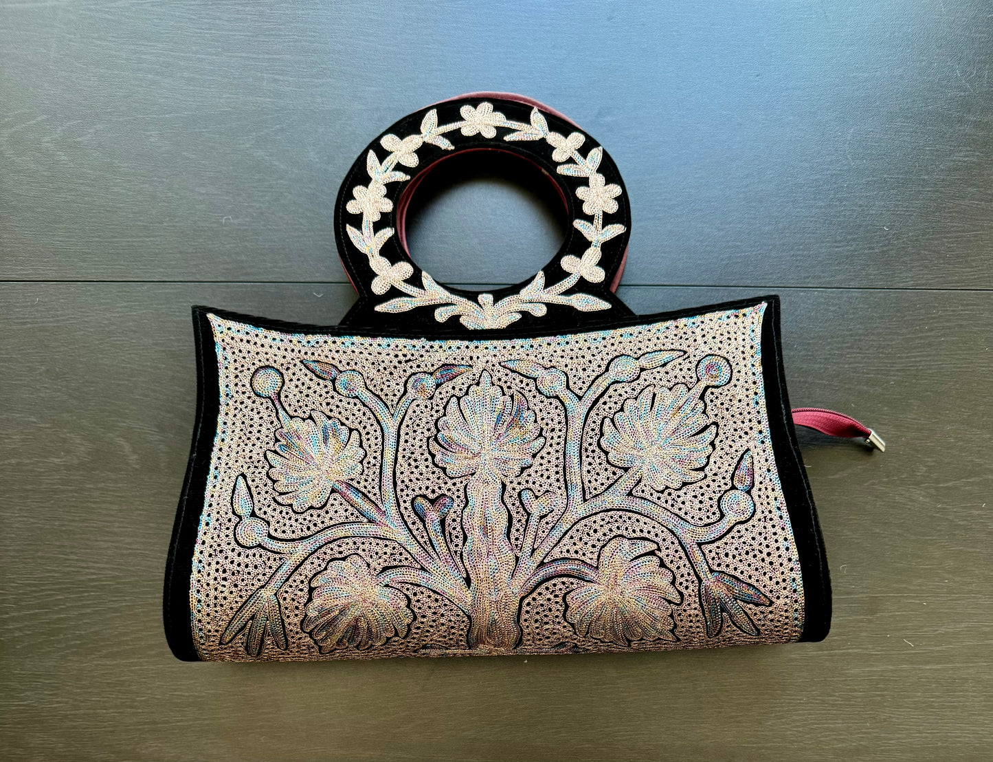Decorative handbag with floral pattern Kashmiri embroidery work on a wooden surface
