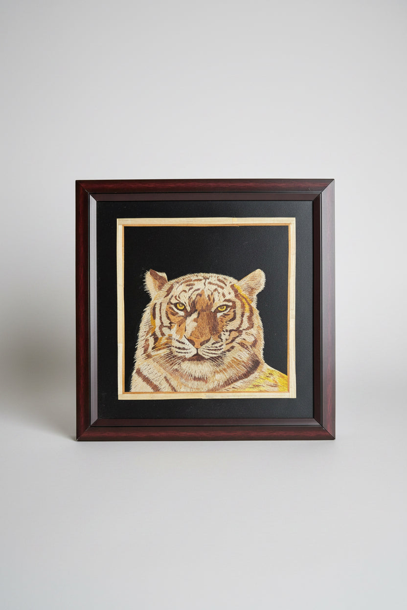 Framed Kerala Rice straw artwork of a tiger on a dark wooden surface