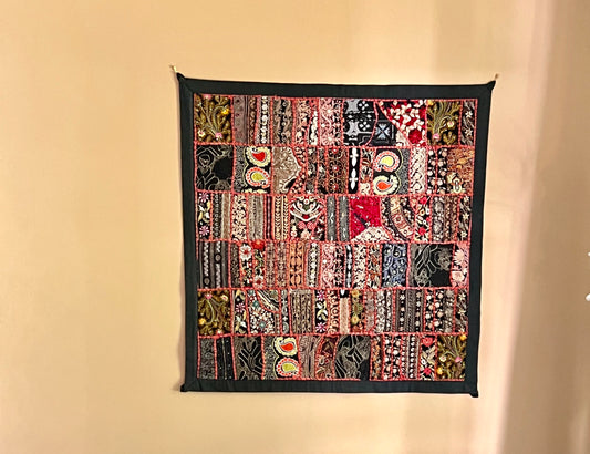 Khambhadia Patchwork quilt with various patterns and colors hanging on a beige wall.