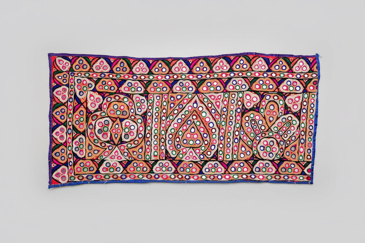 Colorful Kutchi embroidery tapestry with intricate patterns on a gray background