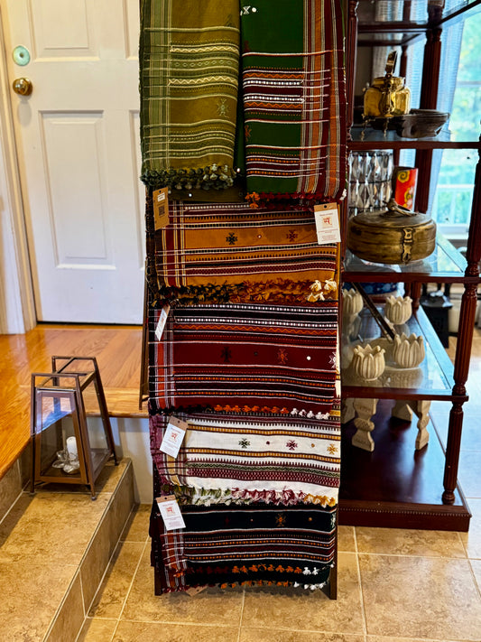 Display of patterned wool shawls on a rack in a store setting