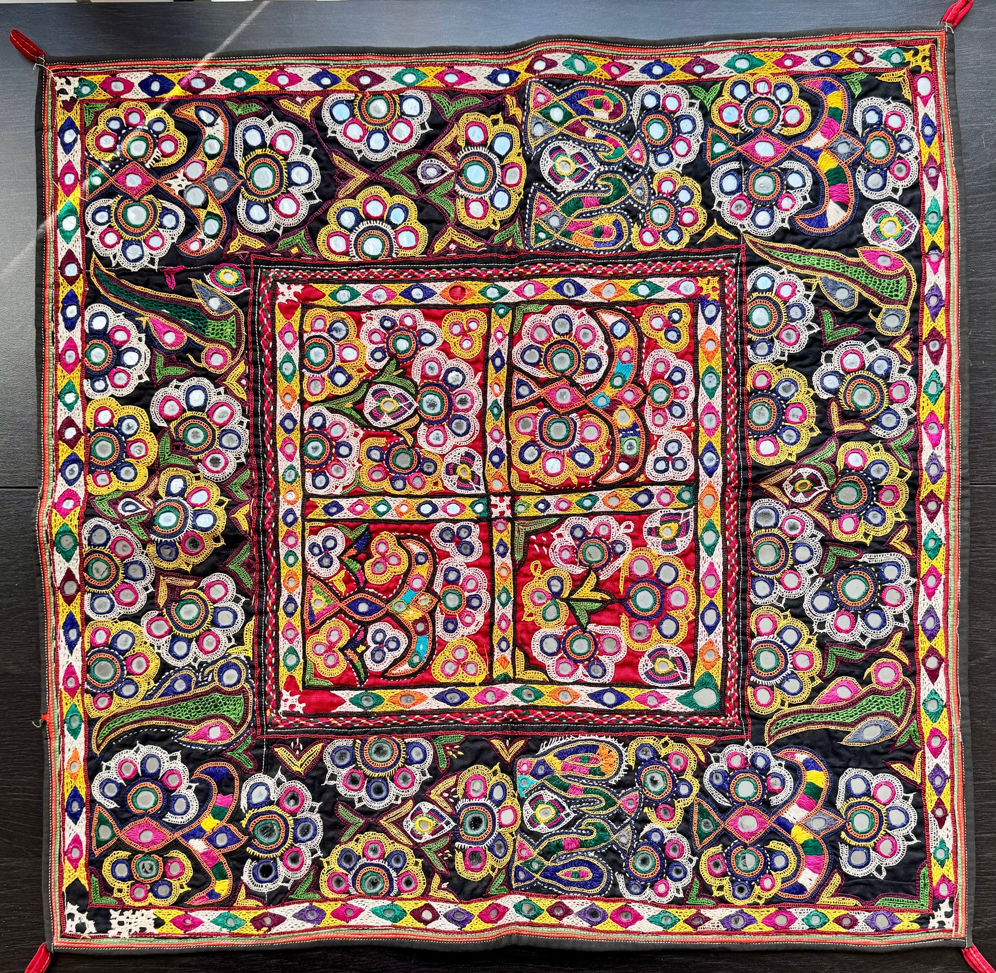 Colorful Kutchi embroidered wall textile with intricate patterns on a dark background