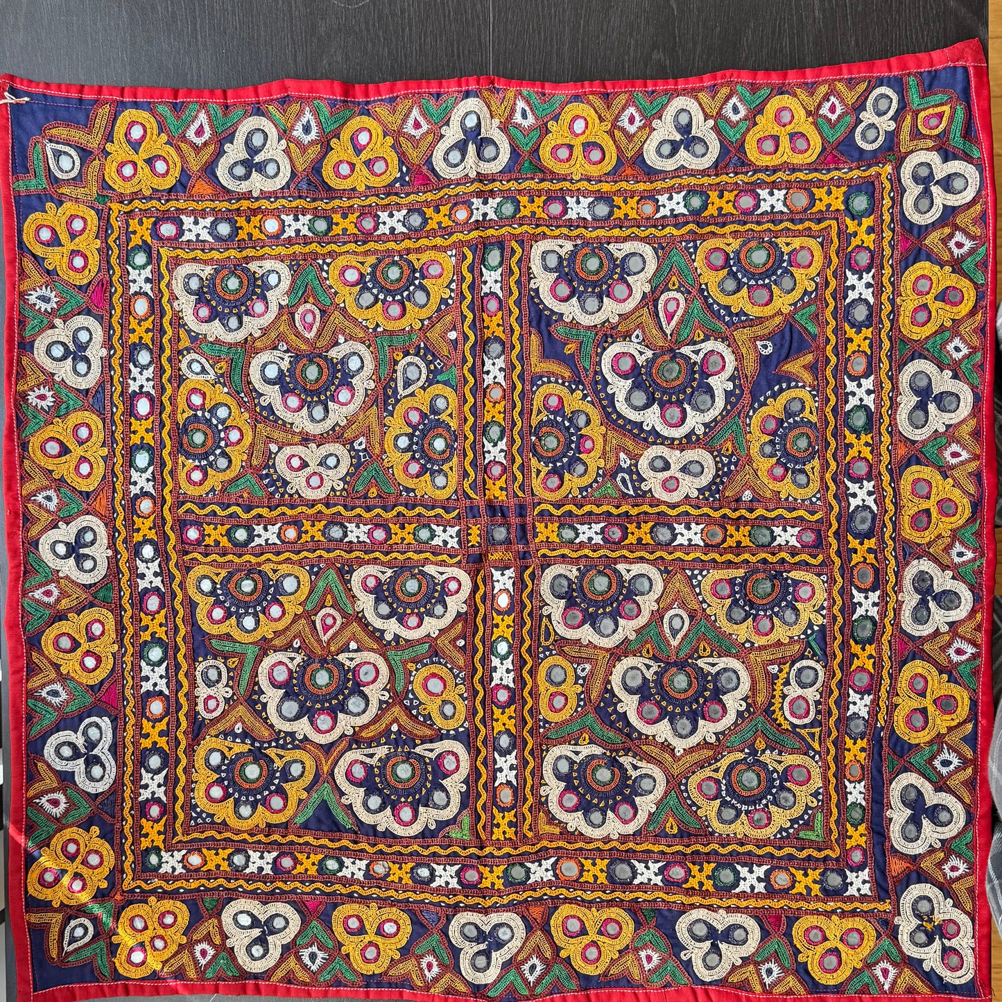 Colorful Kutchi embroidered fabric with intricate patterns on a wooden surface