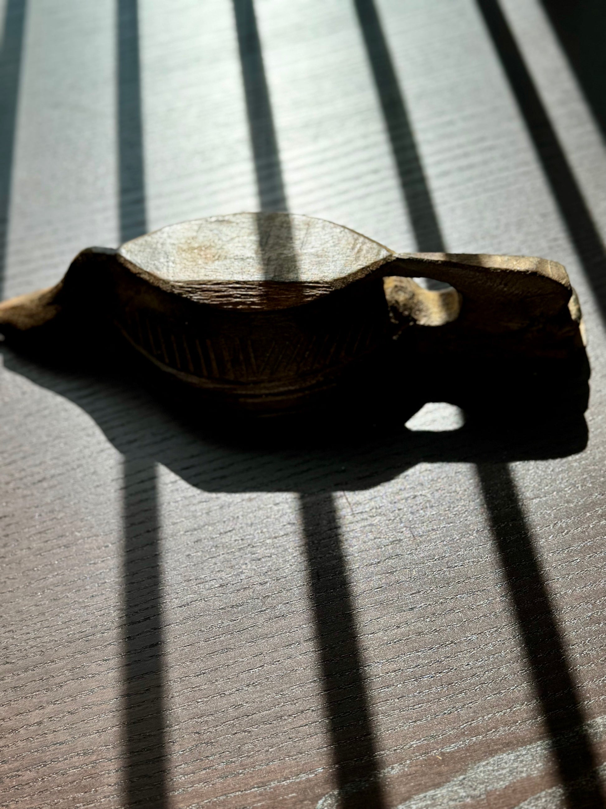 Wooden bowl on a textured surface with shadows