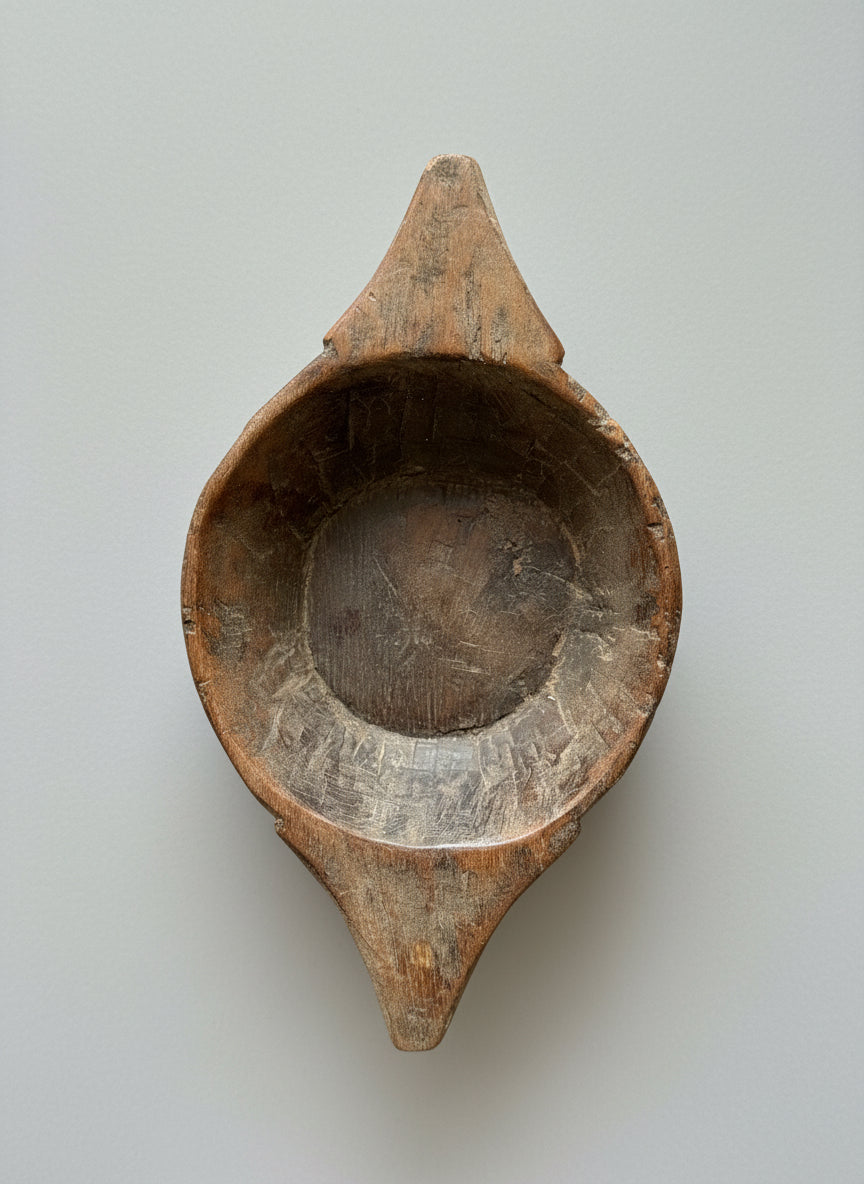 Wooden decorative bowl with a circular handle on a textured surface