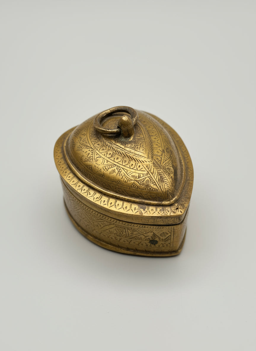 Brass decorative box with intricate designs on a reflective surface