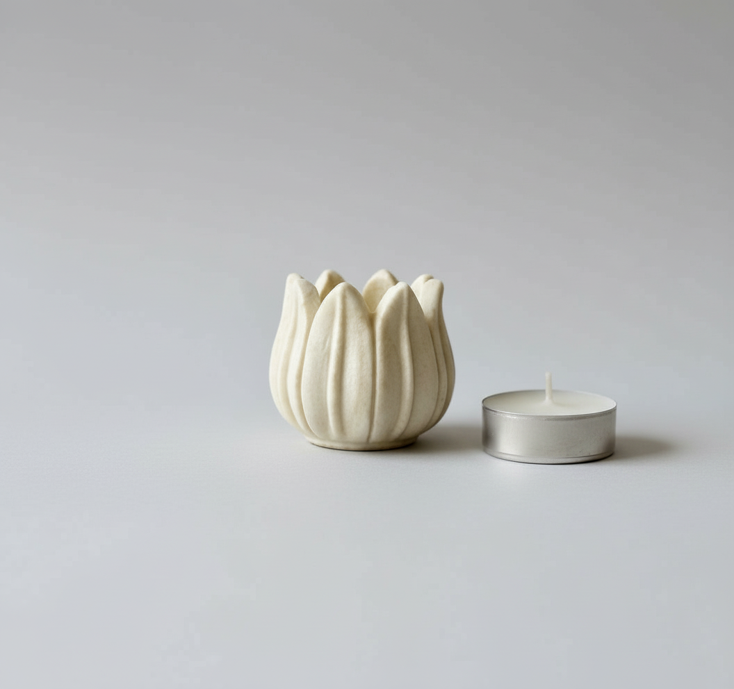 White tulip-shaped candle holder with a small tealight candle on a light gray background