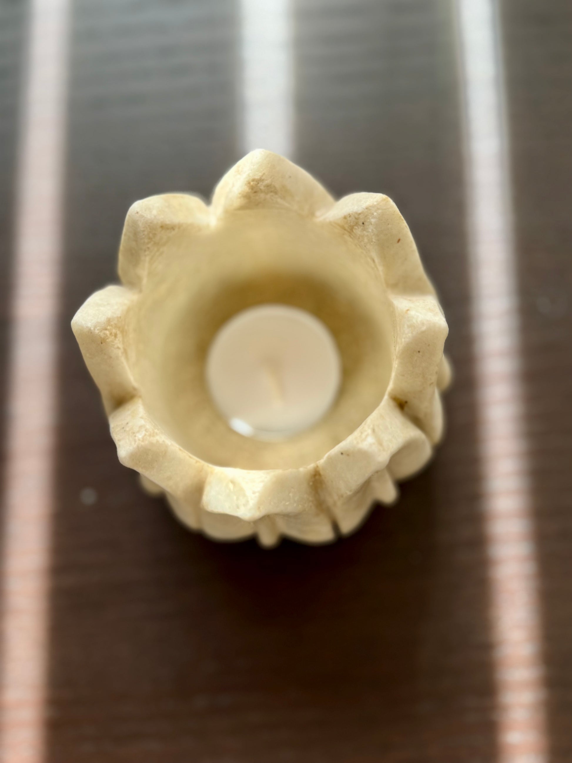 Decorative marble candle holder with a white candle on a metallic surface