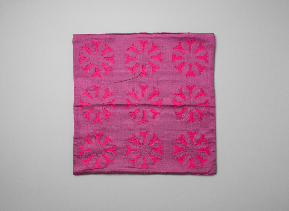 Pink fabric with red geometric patterns on a gray background
