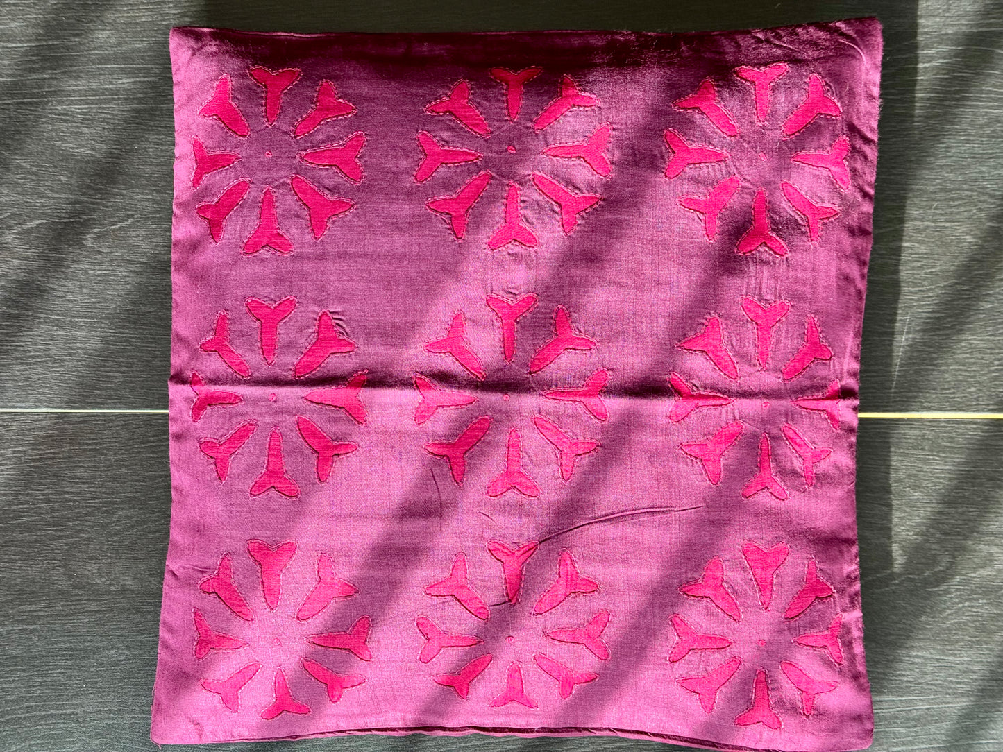 Pink fabric with red floral patterns on a textured surface