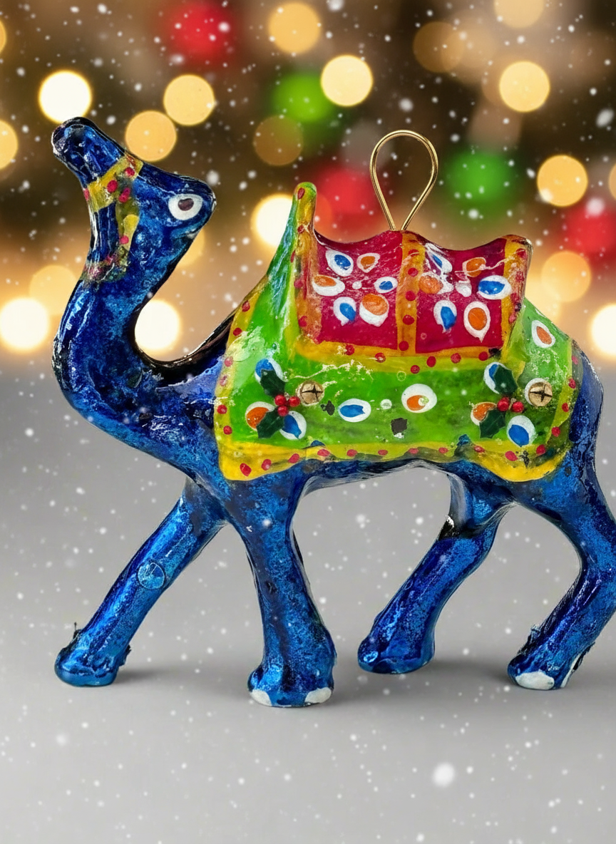 Colorful camel-shaped Christmas ornament with a decorated saddle against a festive background.