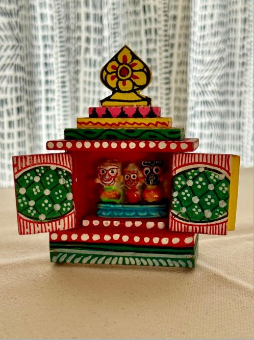 Colorful wooden temple model with intricate designs on a neutral background