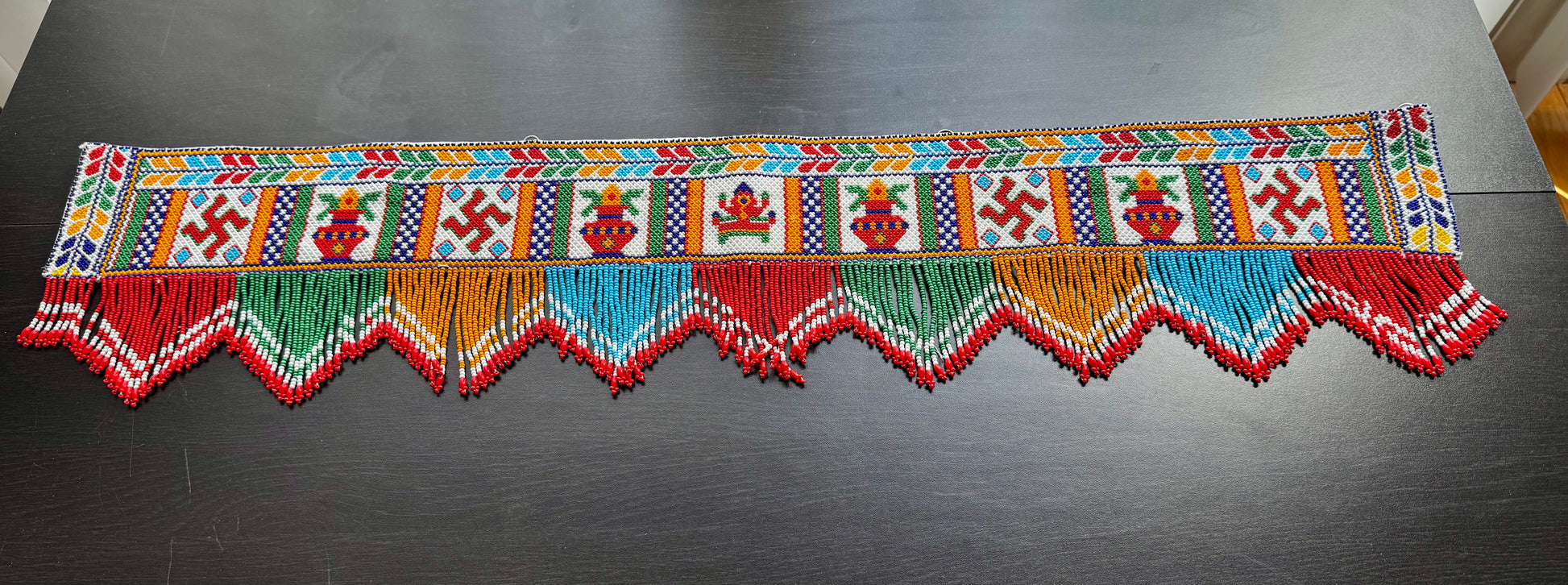Decorative Motikaam valance with colorful patterns on a dark surface