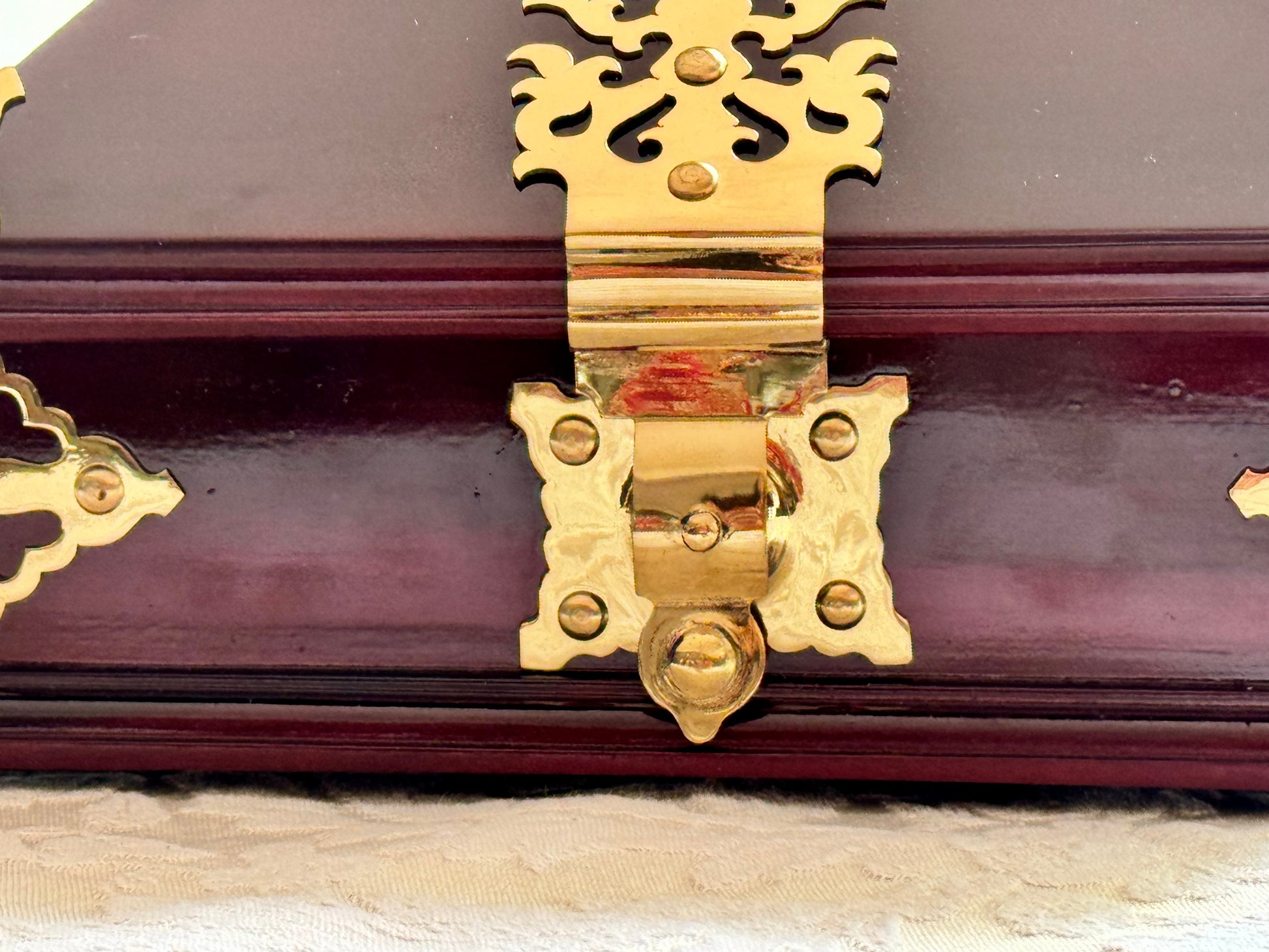 Close-up of rosewood and brass Netturpeti, with a decorative hinge on a wooden surface