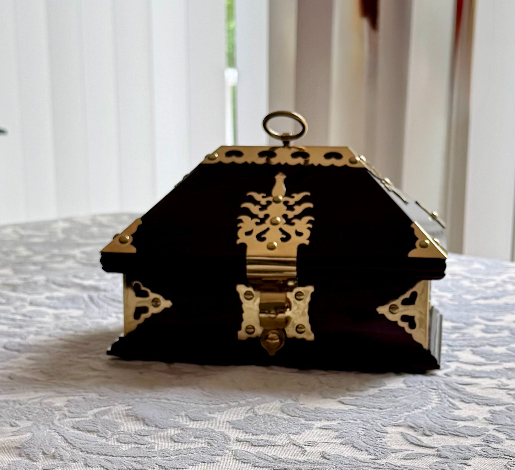 Decorative rosewood and brass jewelry box, Netturpeti, on a textured surface with a blurred background