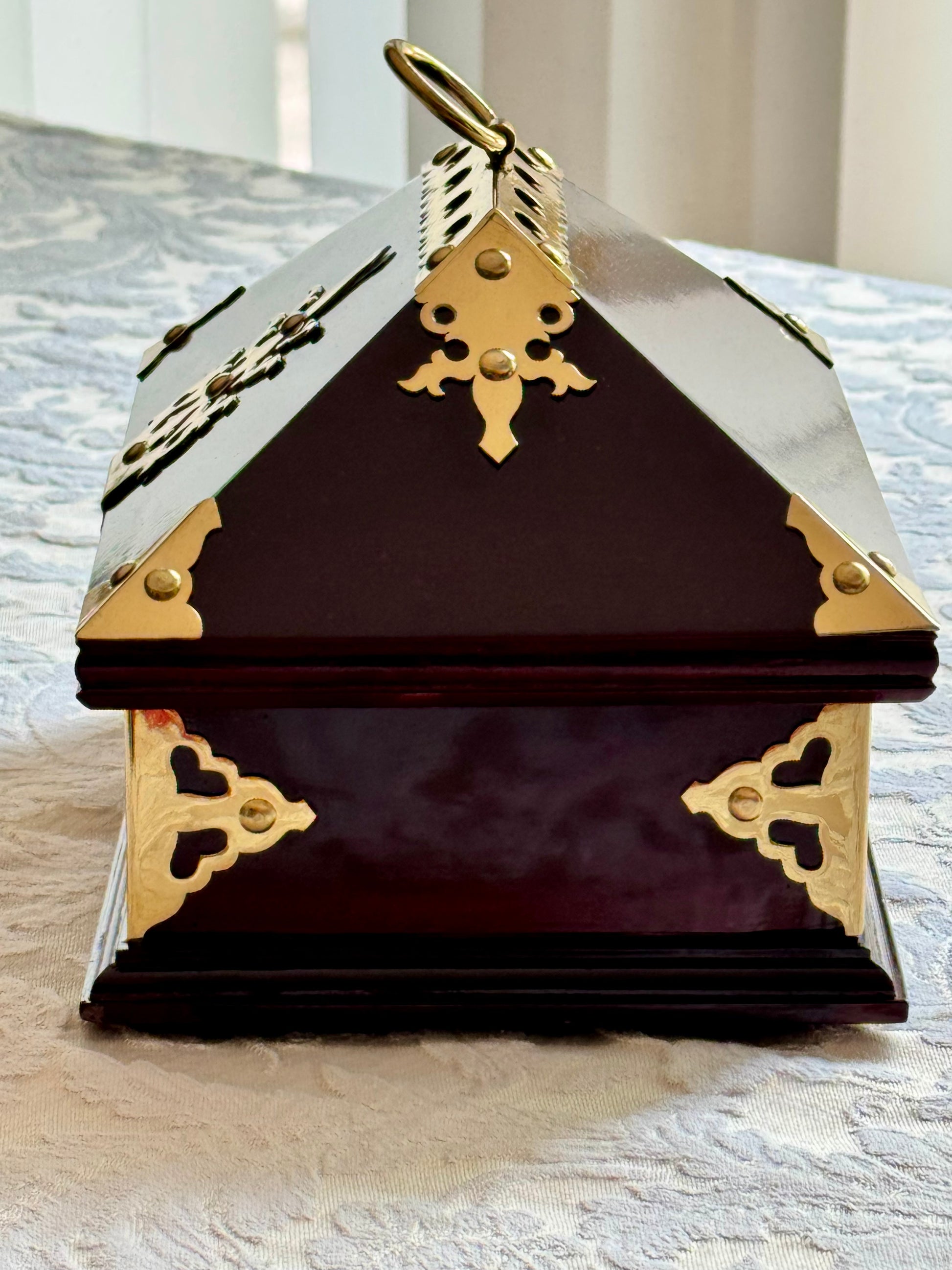 Decorative rosewood jewelry Netturpeti box with brass accents on a textured surface