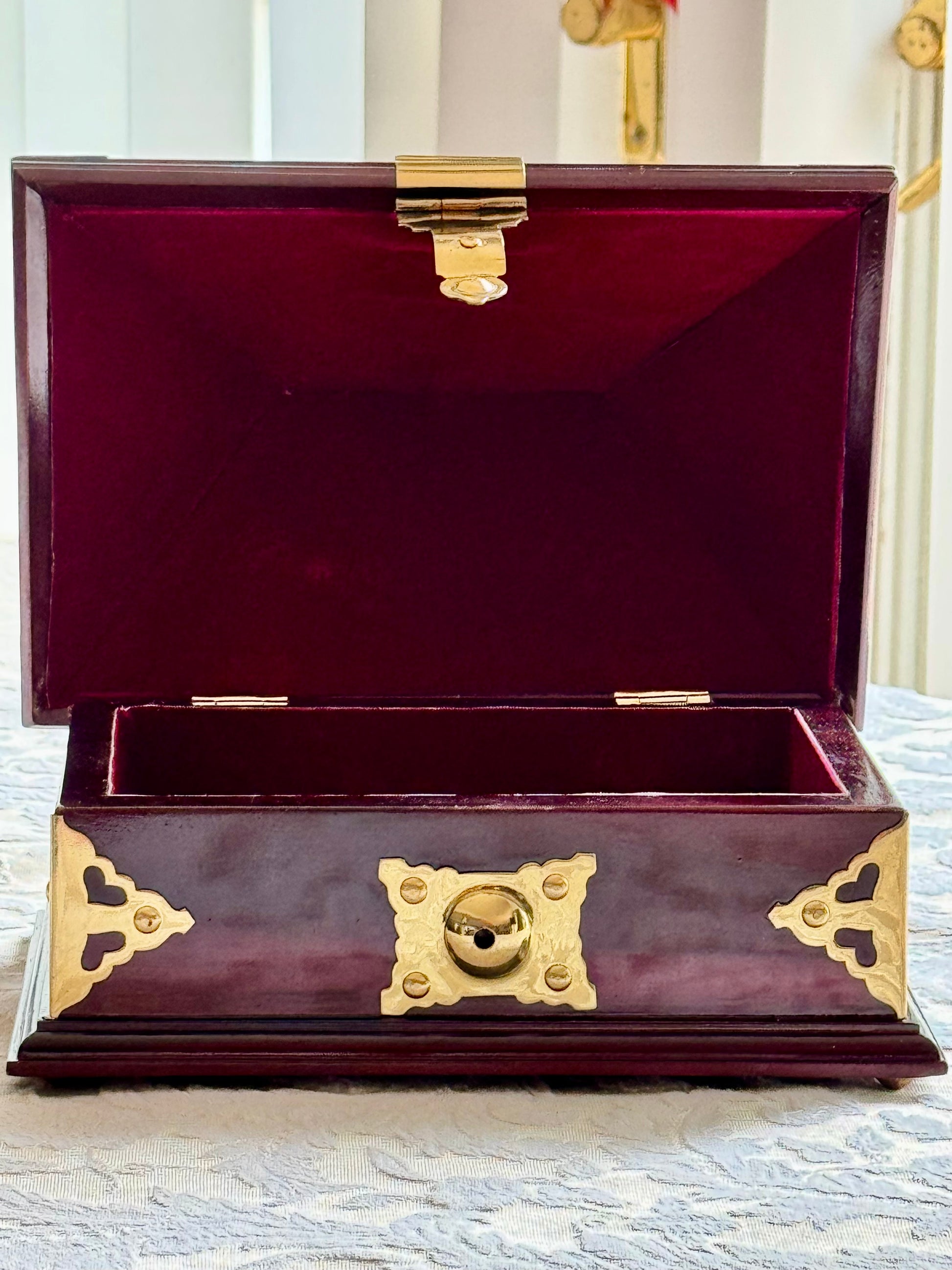Rosewood and brass Netturpeti jewelry box with gold accents on a textured surface