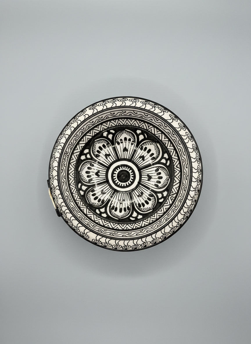 Decorative black and white plate with floral pattern on a wooden surface