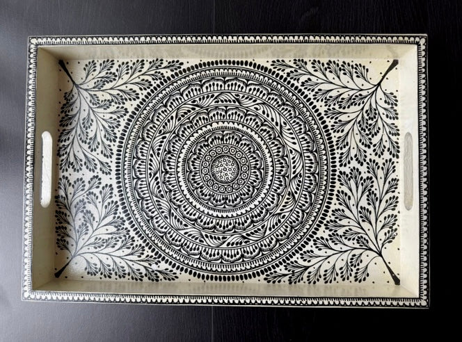 Decorative tray with intricate black and white pattern on a dark background