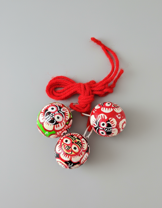 Three red and white decorative buttons with black and white face designs on a gray background.