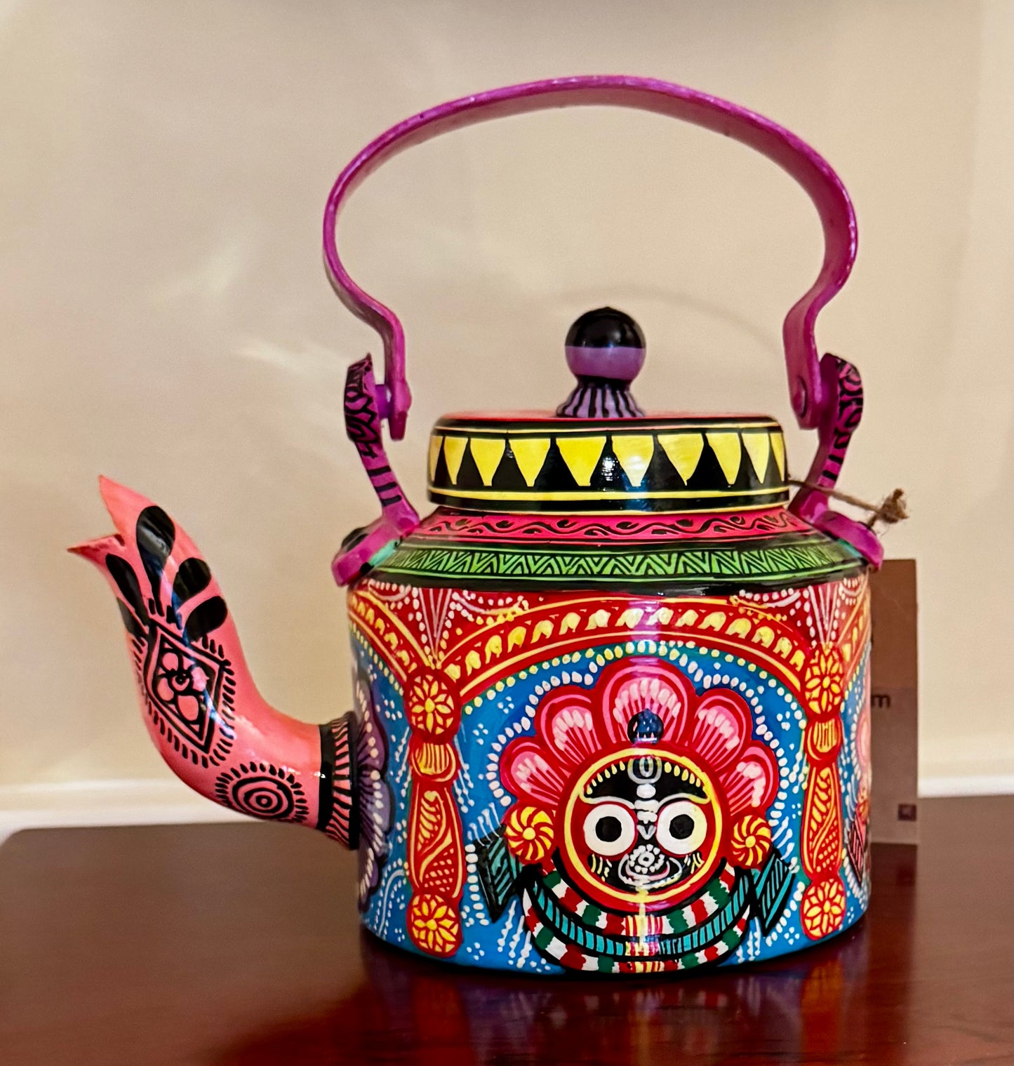 Colorful hand-painted teapot with intricate designs on a wooden surface.