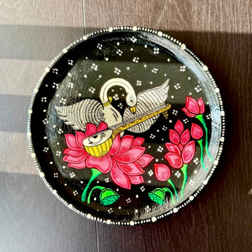 Decorative plate with artistic design of swans and flowers on a dark background