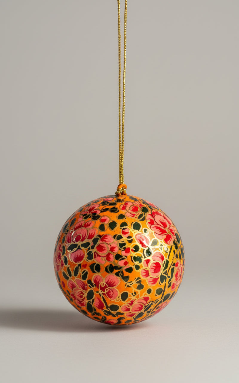 Decorative spherical ornament with floral patterns hanging against a neutral background
