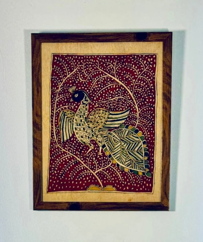 Decorative wall art with a peacock design in a wooden frame on a white wall.