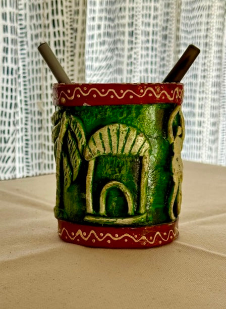 Green Pattachitra art on paper Mache pen holder with red accents on a textured surface