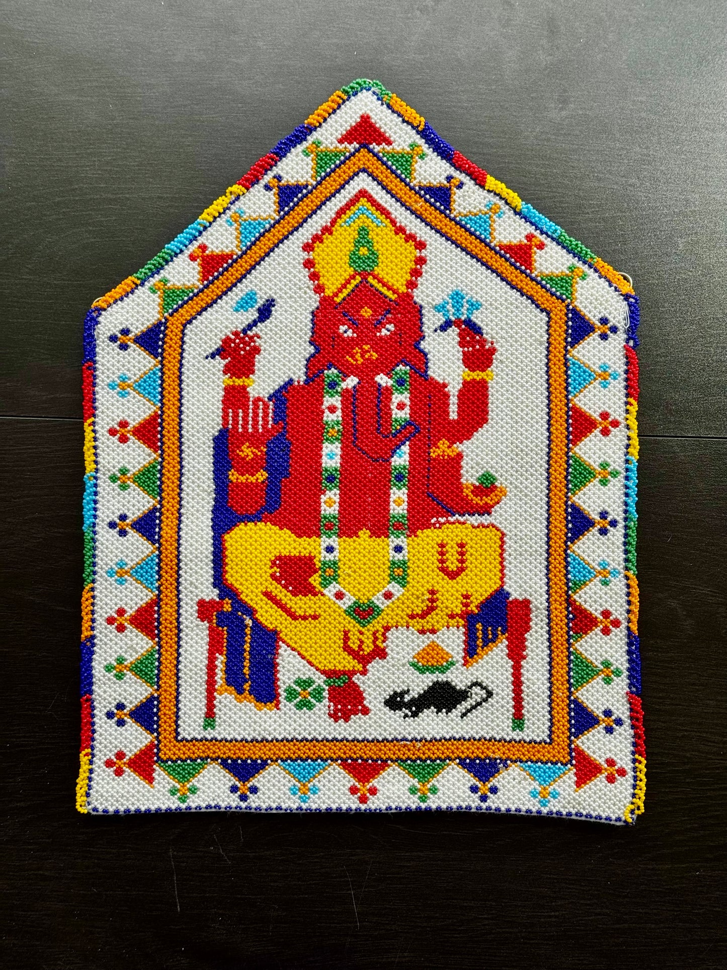 Colorful embroidered patch of a deity with geometric patterns on a dark background
