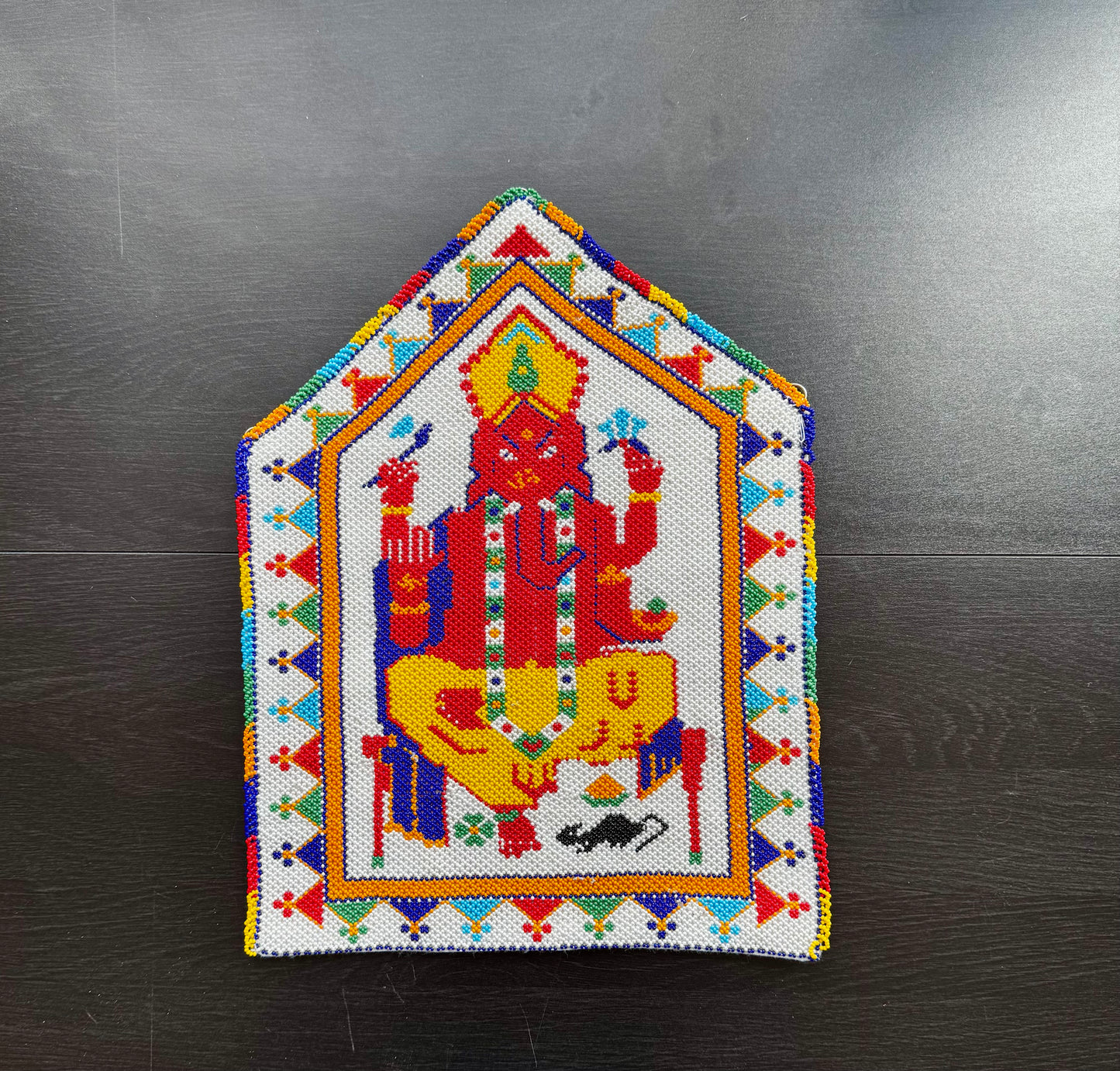 Colorful Motikaam artwork of a deity on a dark surface