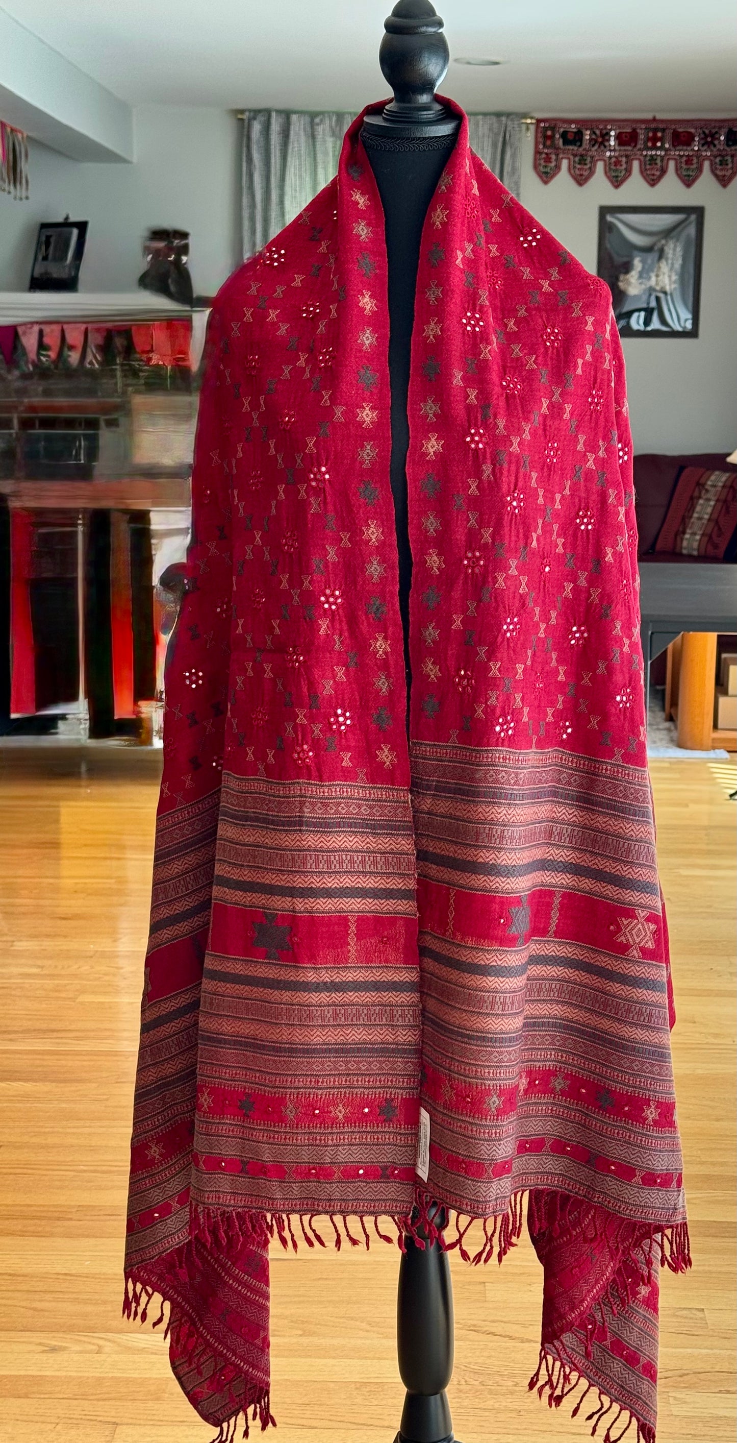 Red patterned scarf embroidered in Kutchi Soof style on a mannequin against a home interior background