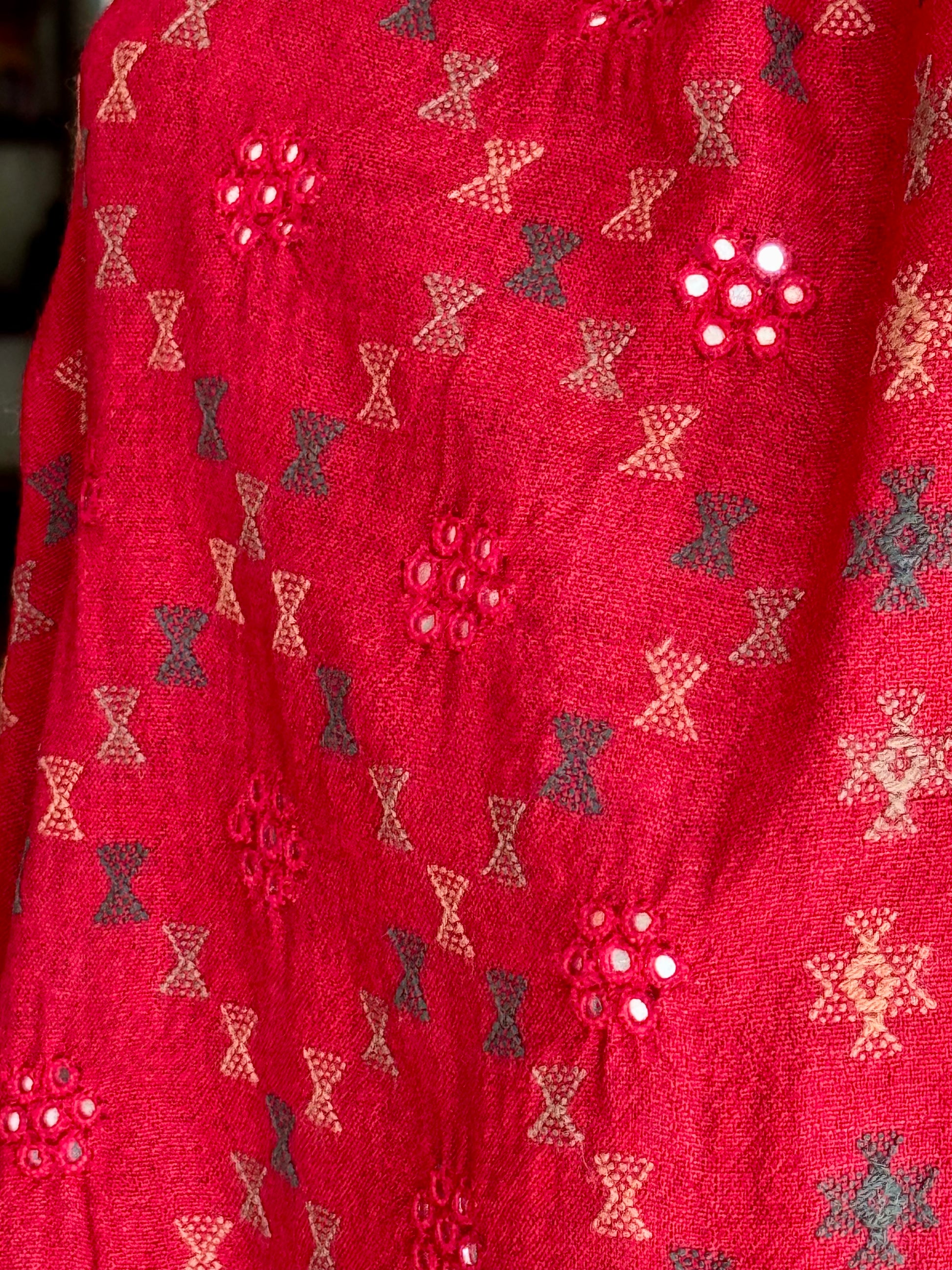 Close-up of a red stole with decorative pattern hand embroidered in Kutchi Soof style..