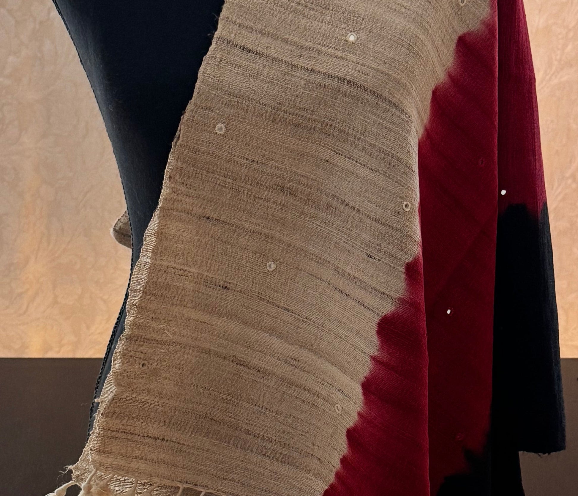 Raw silk stole with a red, black and beige  pattern, draped over a mannequin, in a room with a window.