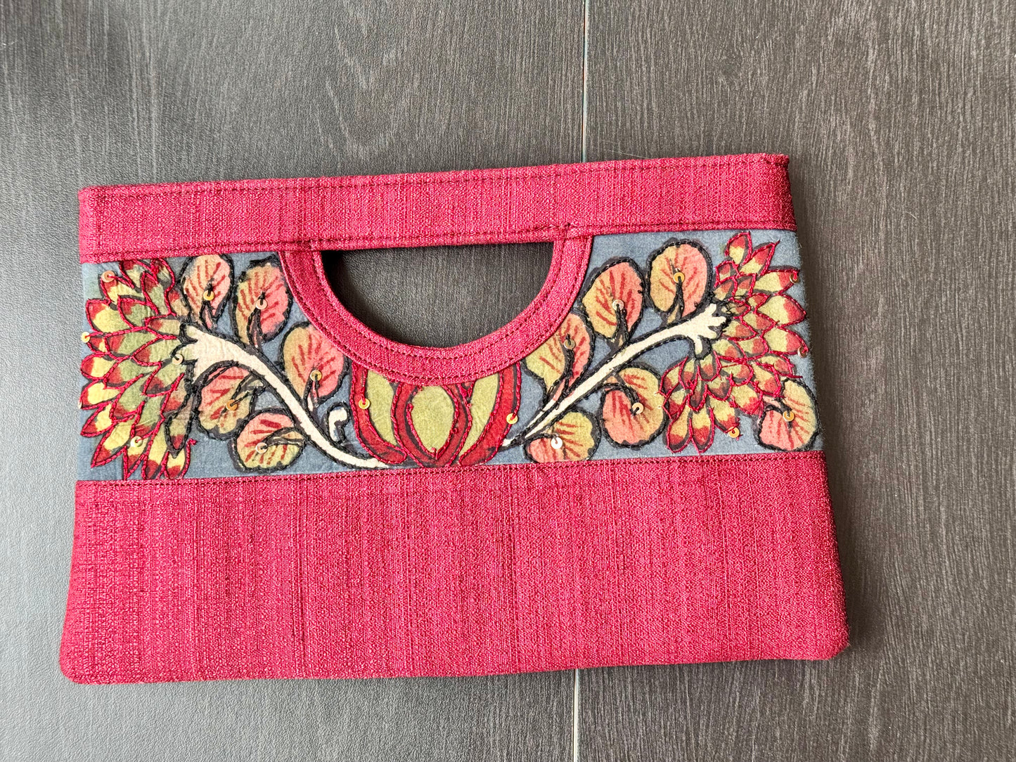 A collection of hand-painted kalamkari clutch purses in various colors, featuring intricate patterns.