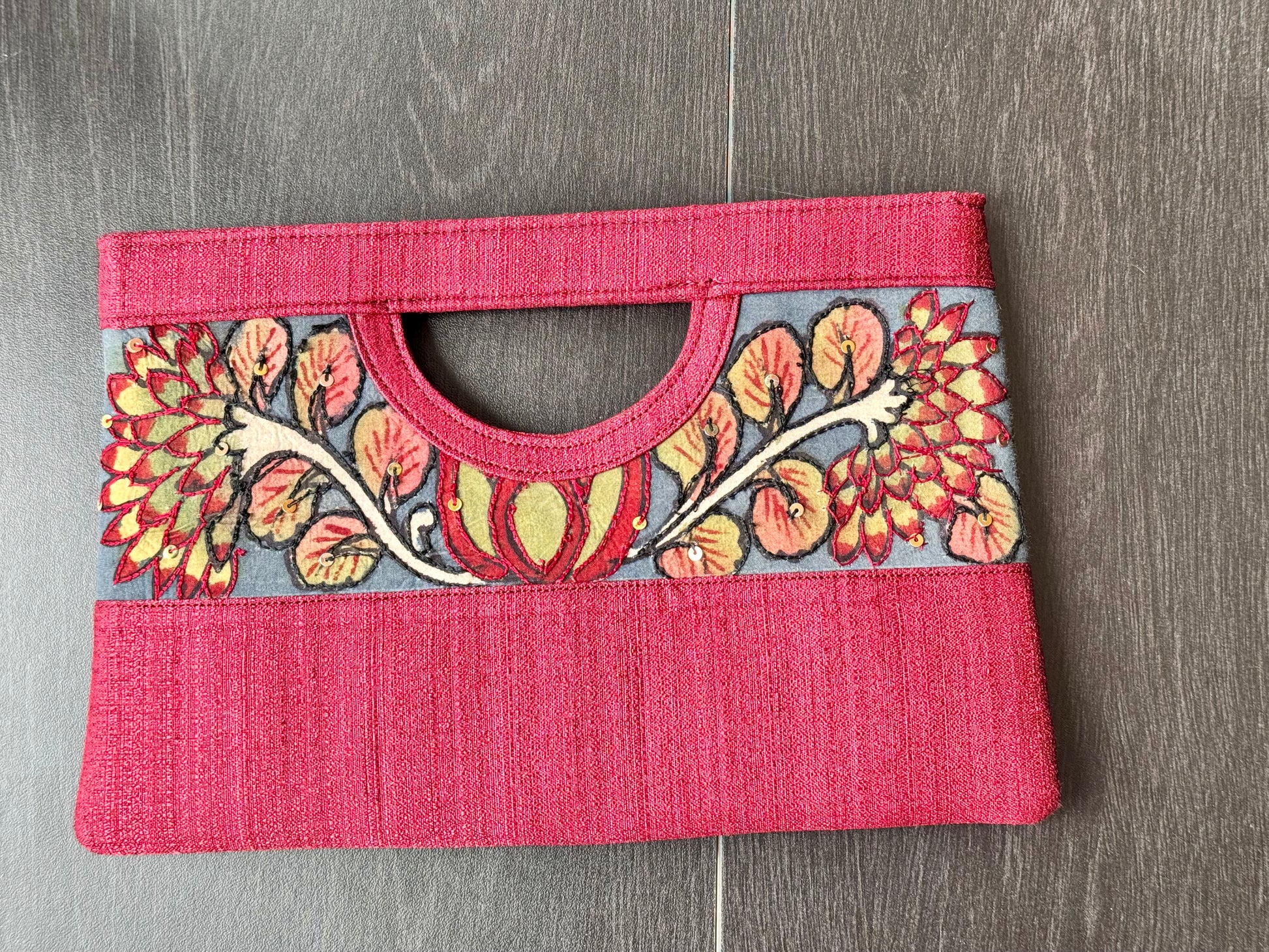 A collection of hand-painted kalamkari clutch purses in various colors, featuring intricate patterns.