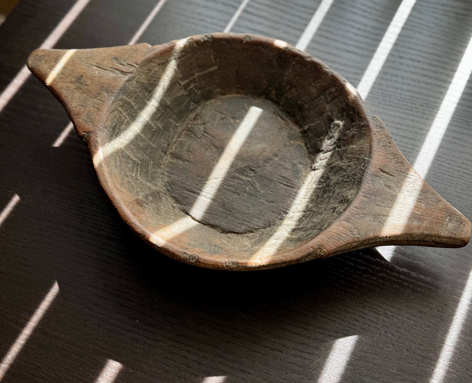 Vintage Wood Engraved Oval Bowls displayed on a surface with interesting light patterns.