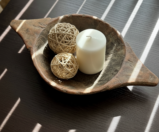 Decorative bowl with a candle and twine balls on a textured surface