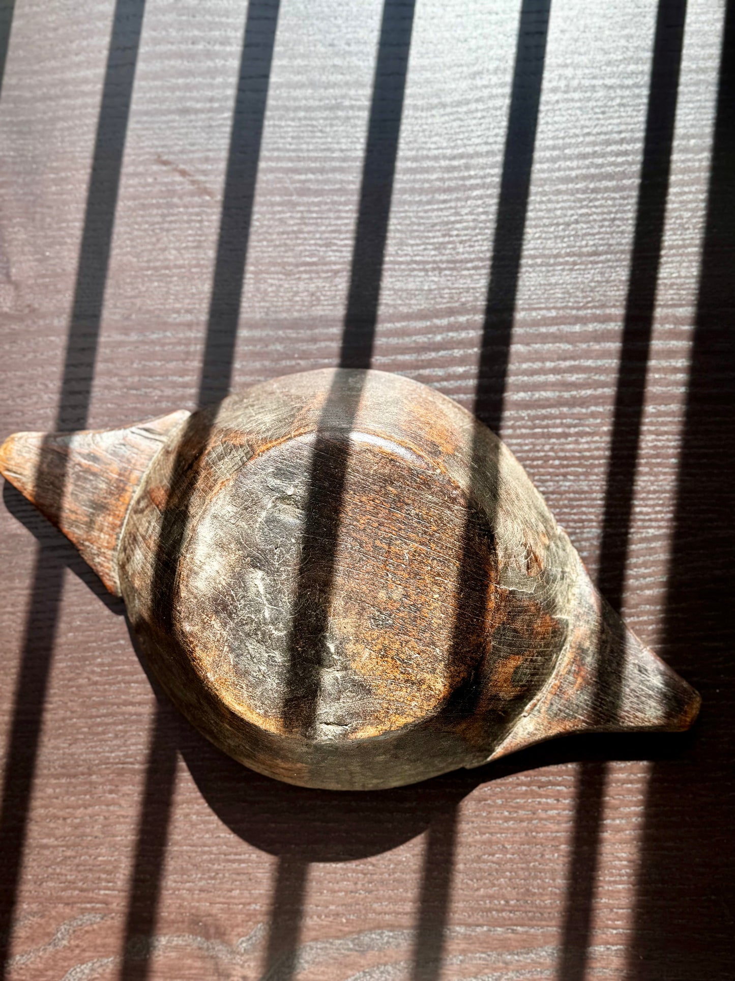 Overturned wood bowl on a sunlit textured background 